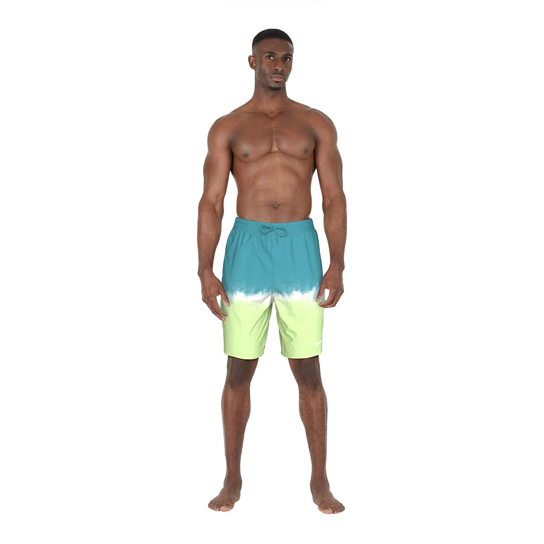 Man wearing a blue and green tie-dye swim shorts on a white background